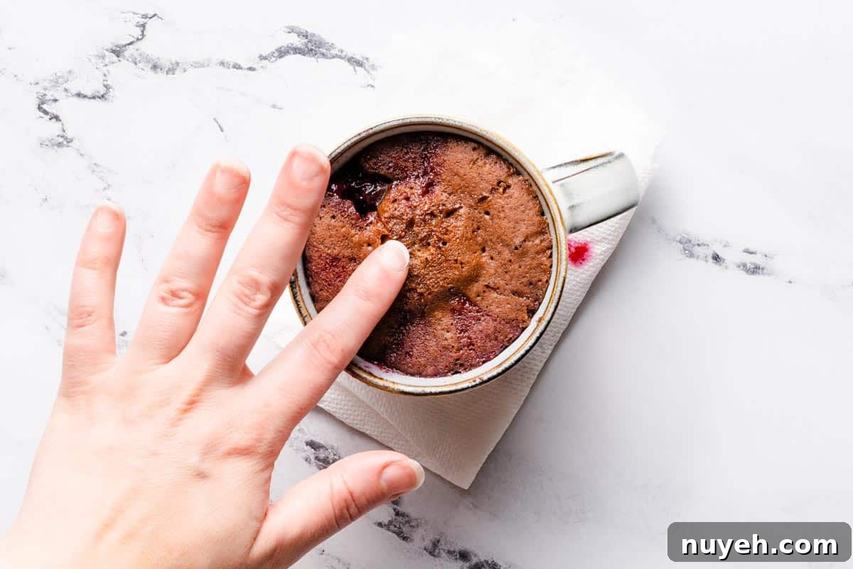 finger touching top of cooked mug cake