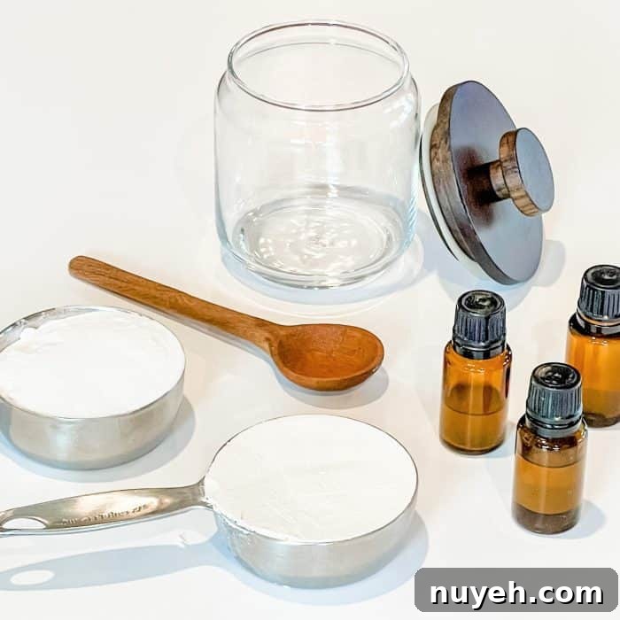 supplies to make diy refrigerator freshener -- glass jar, wooden spoon, essential oil, baking soda in measuring cup, diatomaceous earth in measuring cup