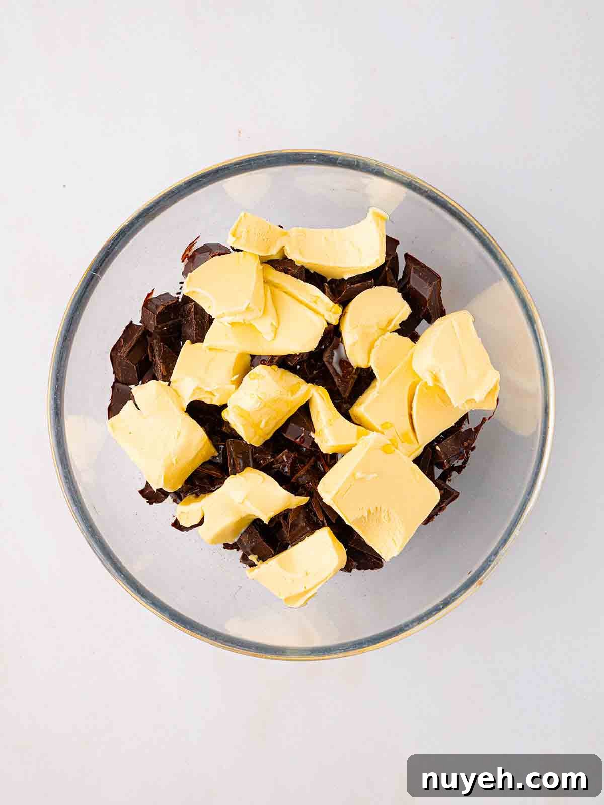 Butter and chocolate chunks in a glass bowl for step 1 in the method for Rocky Road recipe.