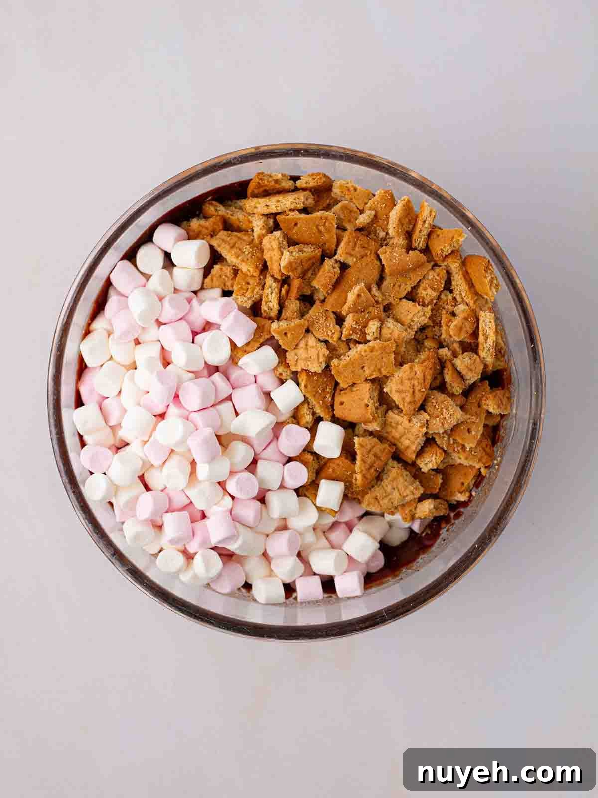 A bowl filled with melted chocolate, marshmallows and digestive biscuits for a Rocky Road recipe.