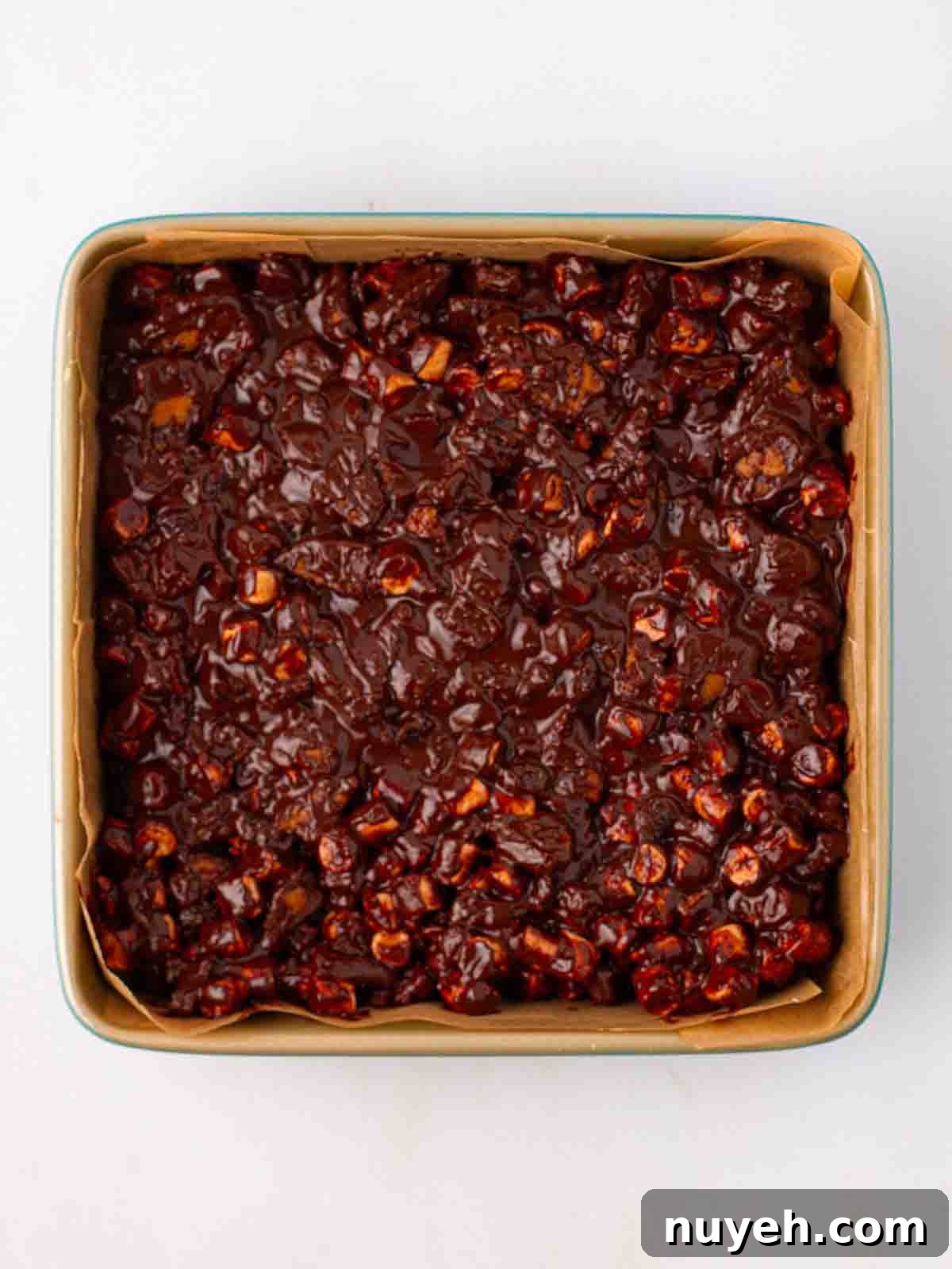 A square tray mixed with chocolate, marshmallow and biscuit for step 4 in the recipe for Rocky Road.