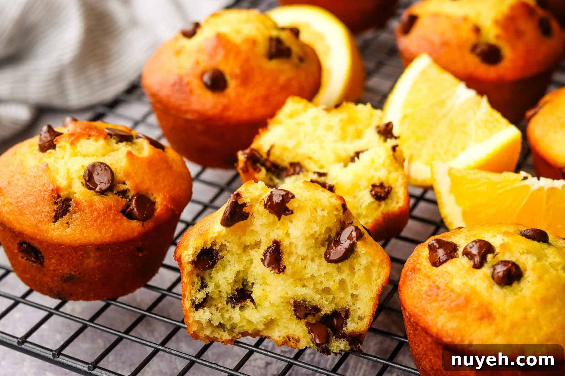 Orange chocolate chip muffins on a cooling rack with one split open.
