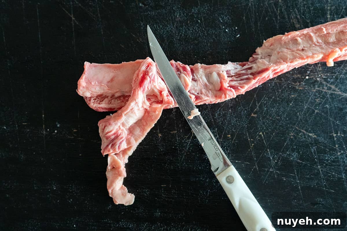 remove layer of cartilage from beef finger ribs with knife.