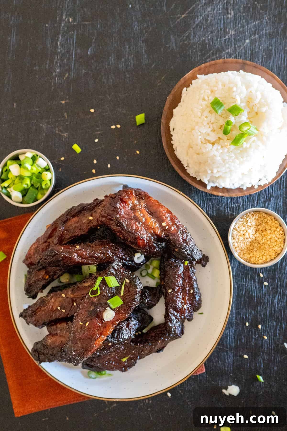 teriyaki beef finger ribs on plate near bowl of rice.