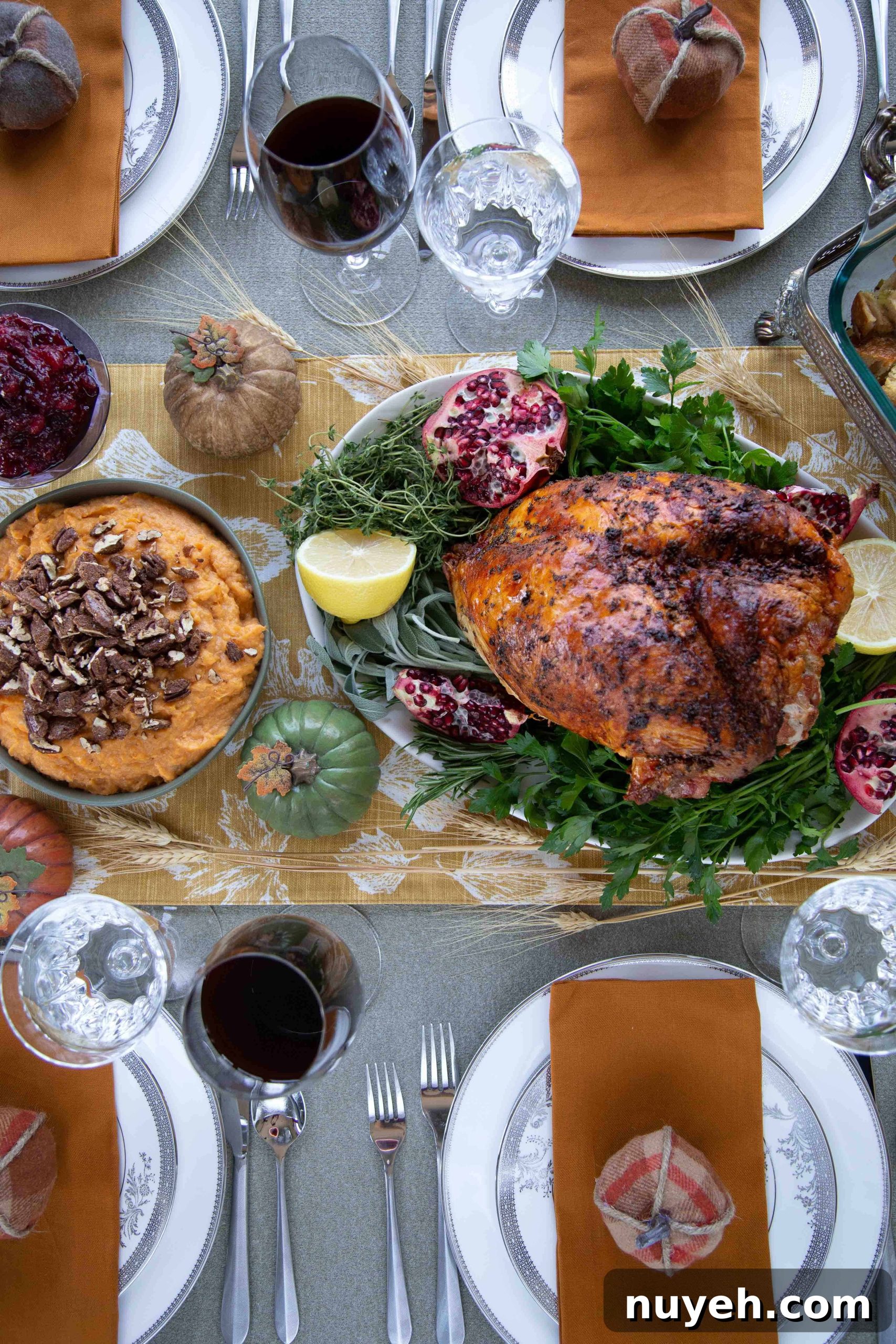 Thanksgiving tablescape with a bone-in turkey breast, mashed sweet potatoes, mini faux pumpkins, and china.