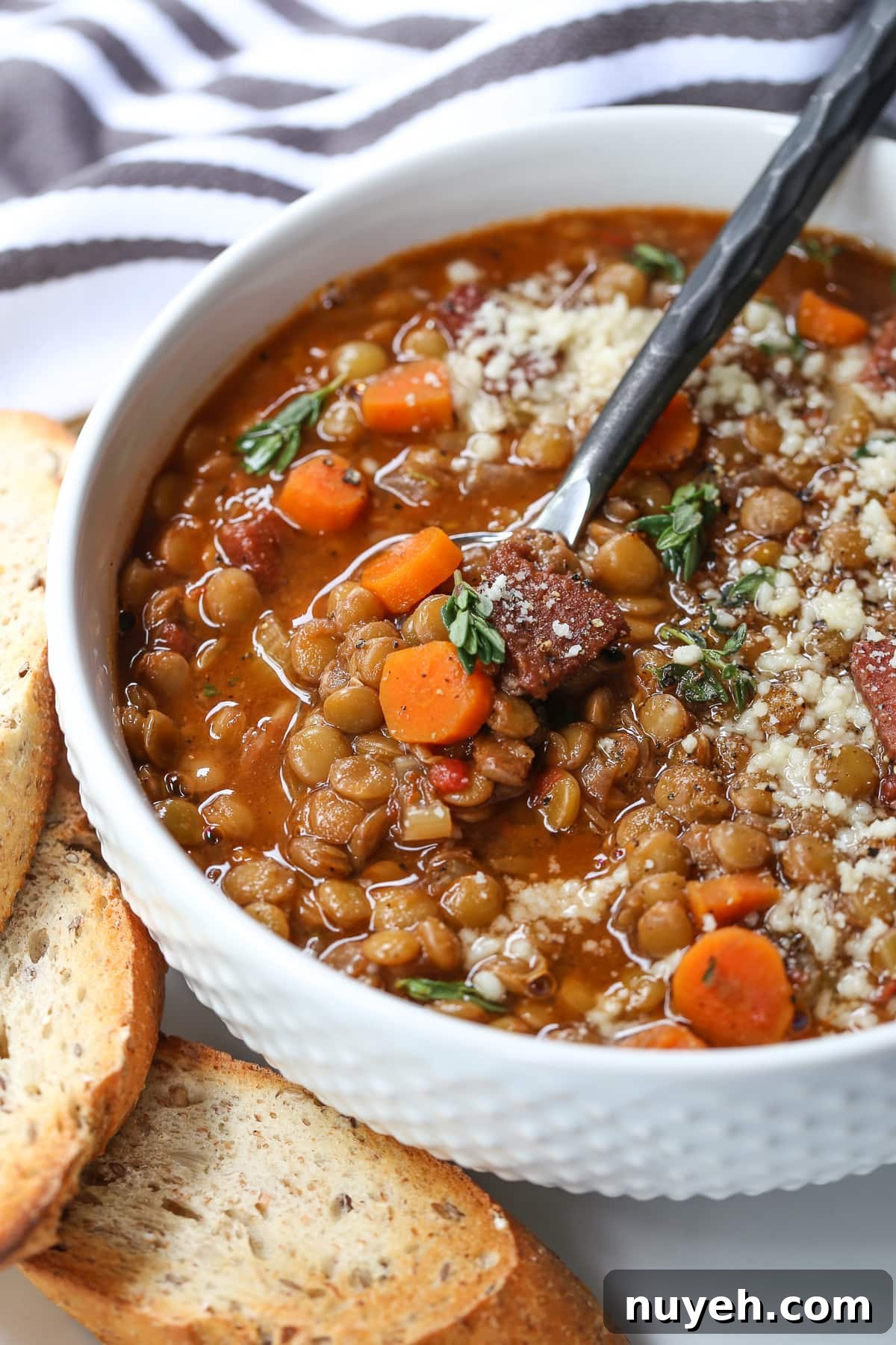 lentil soup with ham in white bowl with spoon