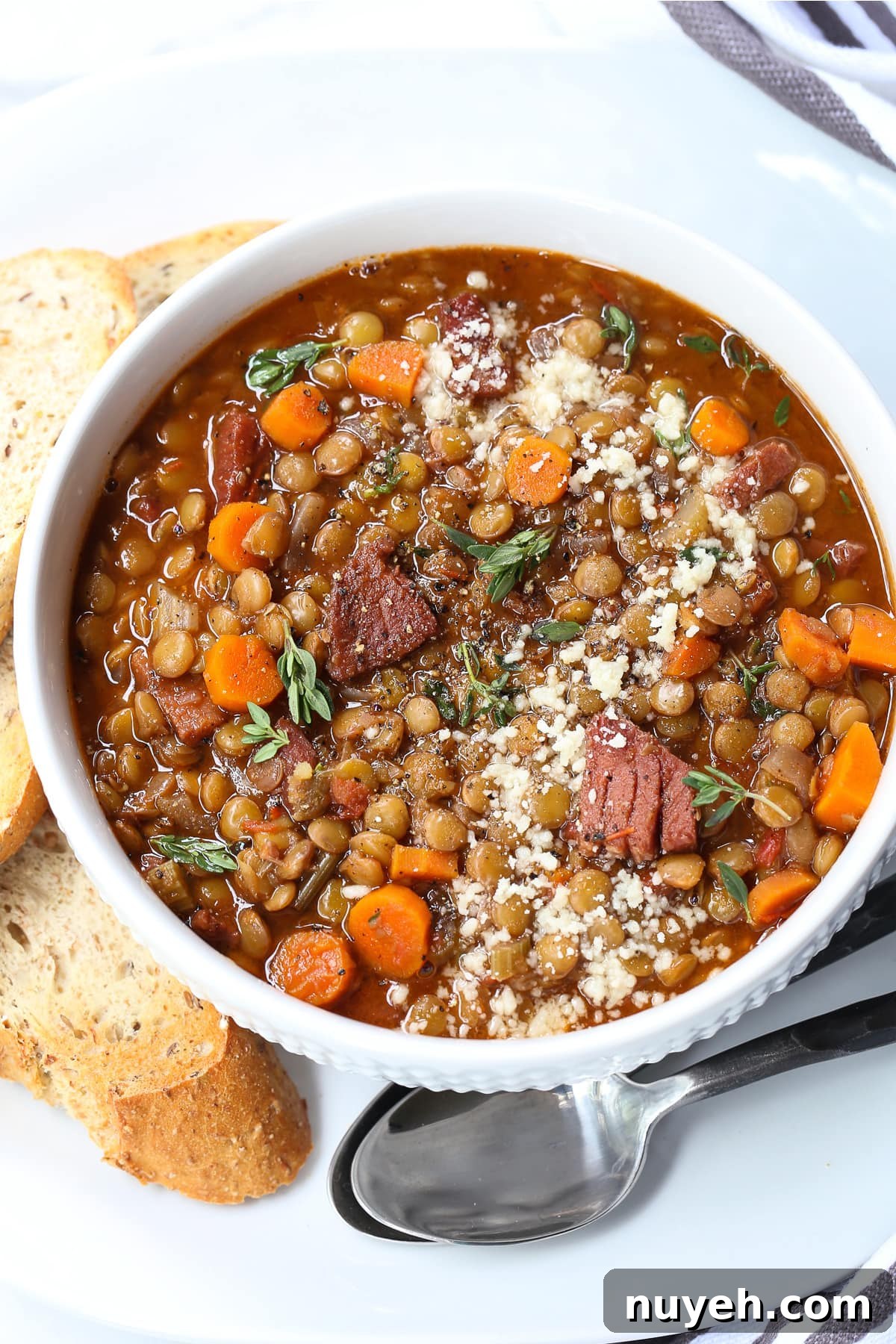 lentil soup with ham in a bowl with toast and spoon on the side