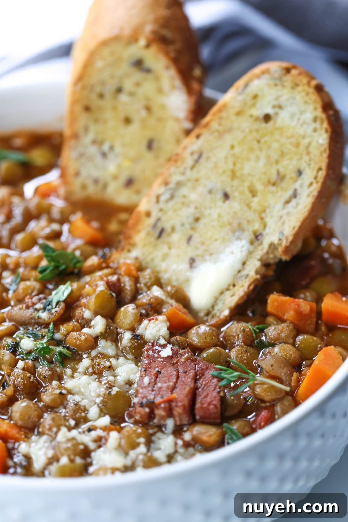 lentil soup with ham and vegetables in white bowl with toast
