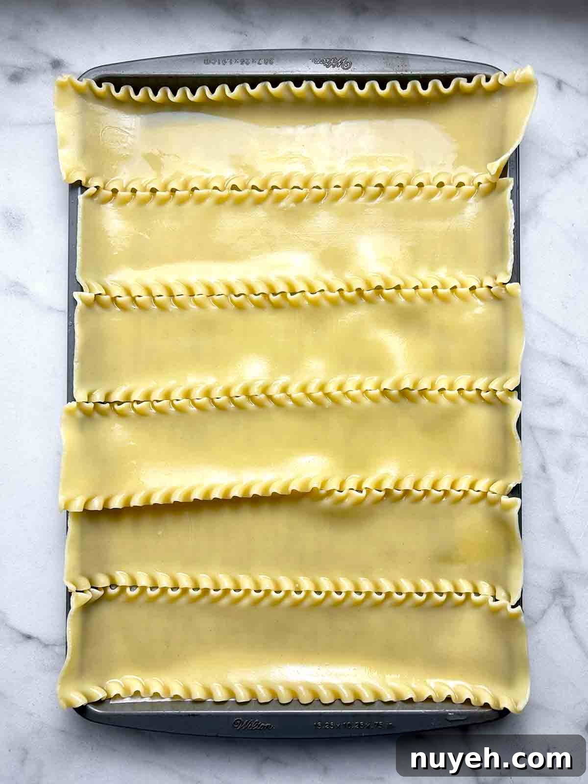 cooked lasagna noodles spread on baking sheet.
