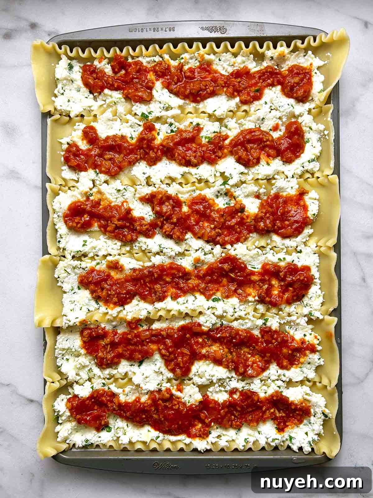 meat sauce and ricotta filling spread onto 6 lasagna noodles on baking sheet.