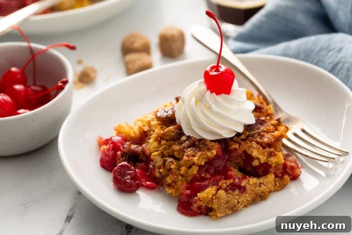 Plated cherry pineapple dump cake topped with whipped cream and a cherry