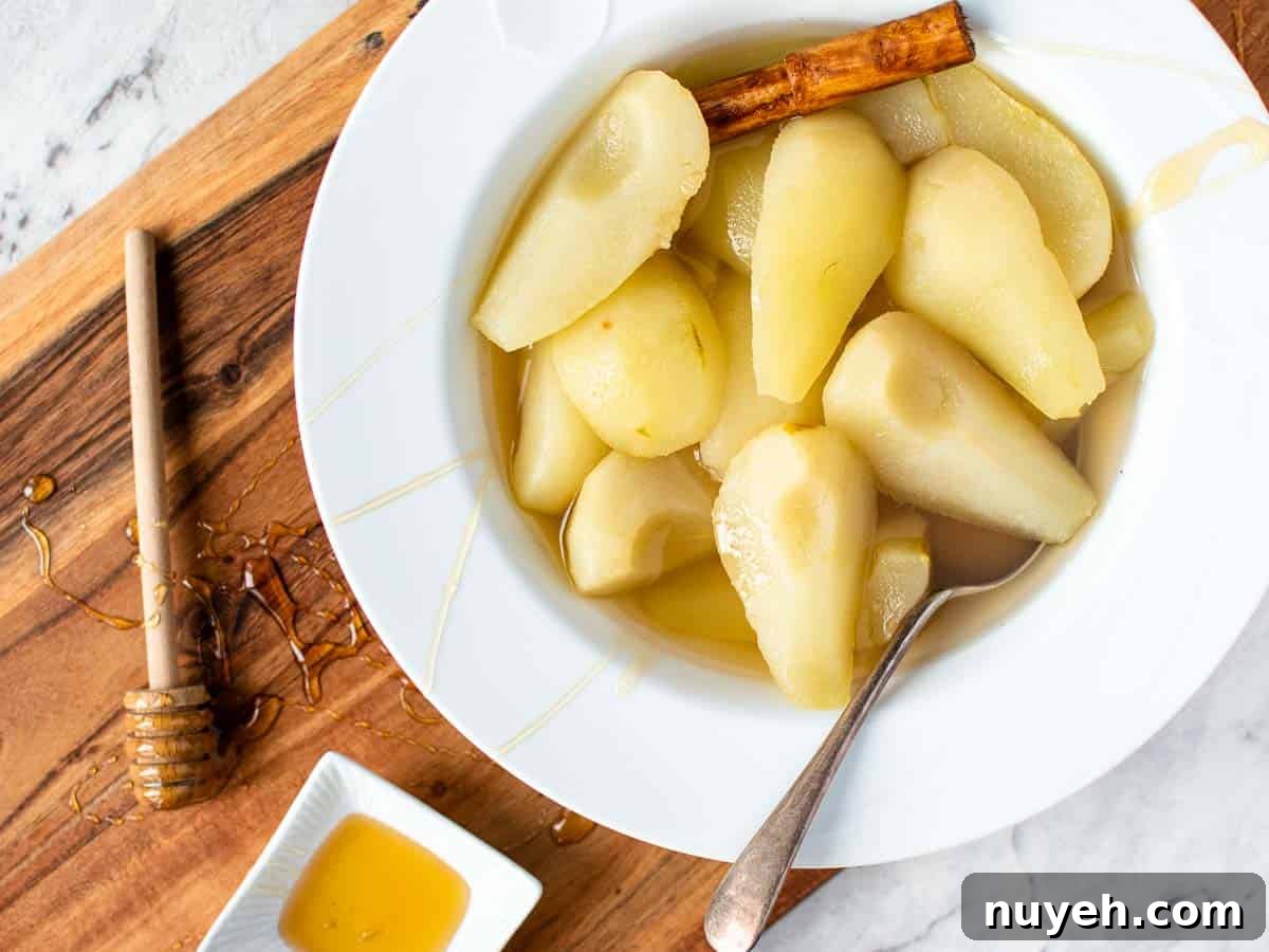 cooked peeled and quartered pears in a white large rimmed bowl with spoon viewed from above.