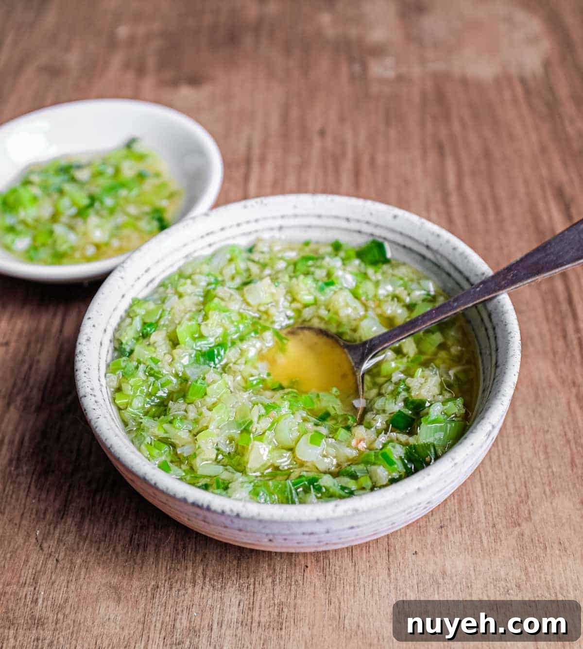 Two small bowls of Chinese Ginger Scallion Sauce with a small serving spoon