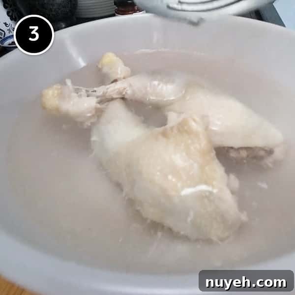 Plunging the cooked chicken portions into a bowl of ice-cold water.