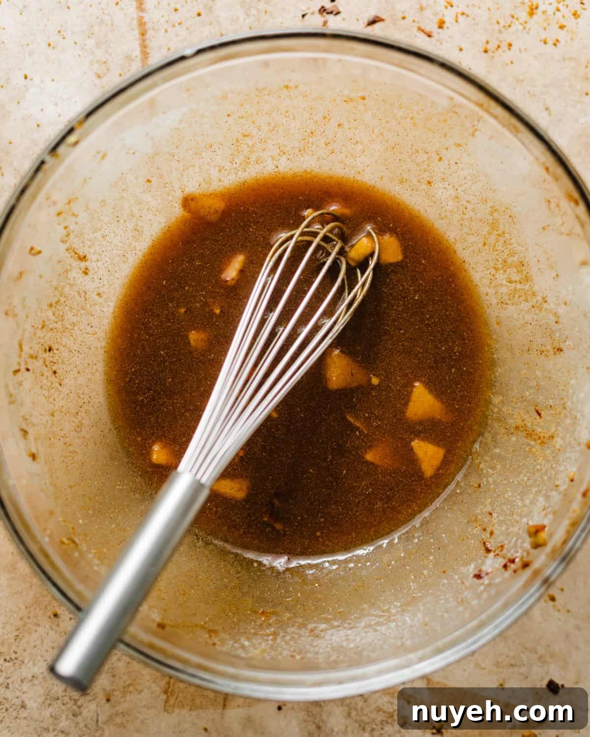 reserved juices from the apples in a bowl with melted butter, apple cider, and cinnamon.