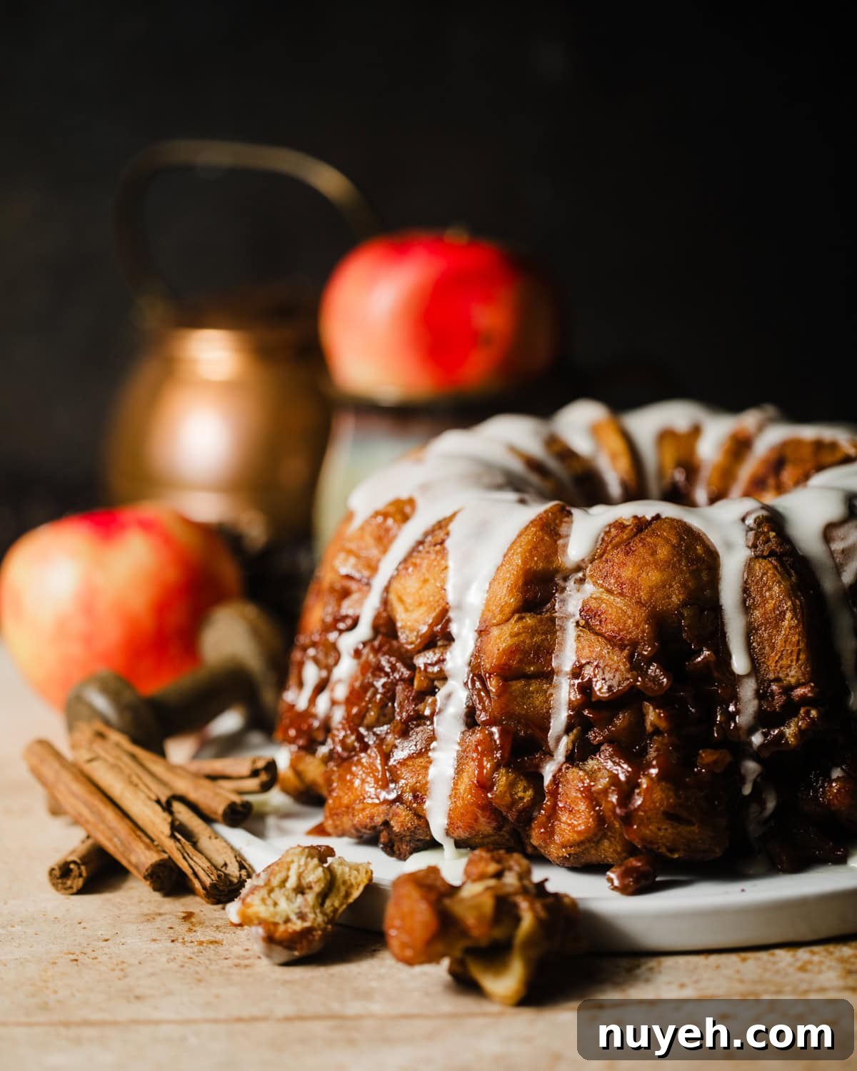 apple monkey bread on a serving plate with apples and cinnamon sticks.