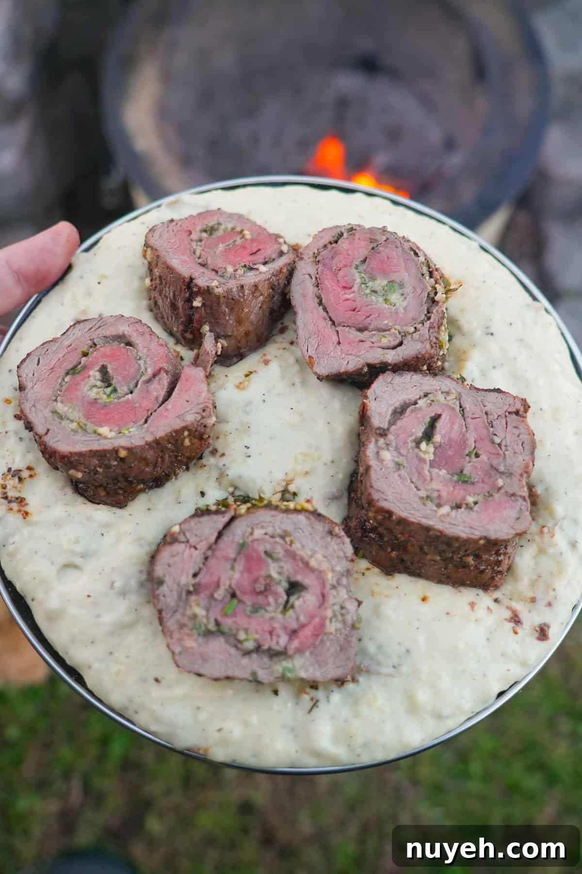 The sliced spiraled tenderloin is plated over a bed of mashed potatoes.