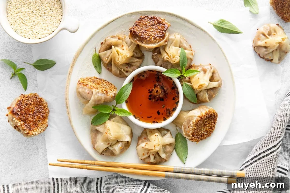 Mushroom vegetarian dumplings on a white plate with chopsticks at the side and garlic chili oil in the center.
