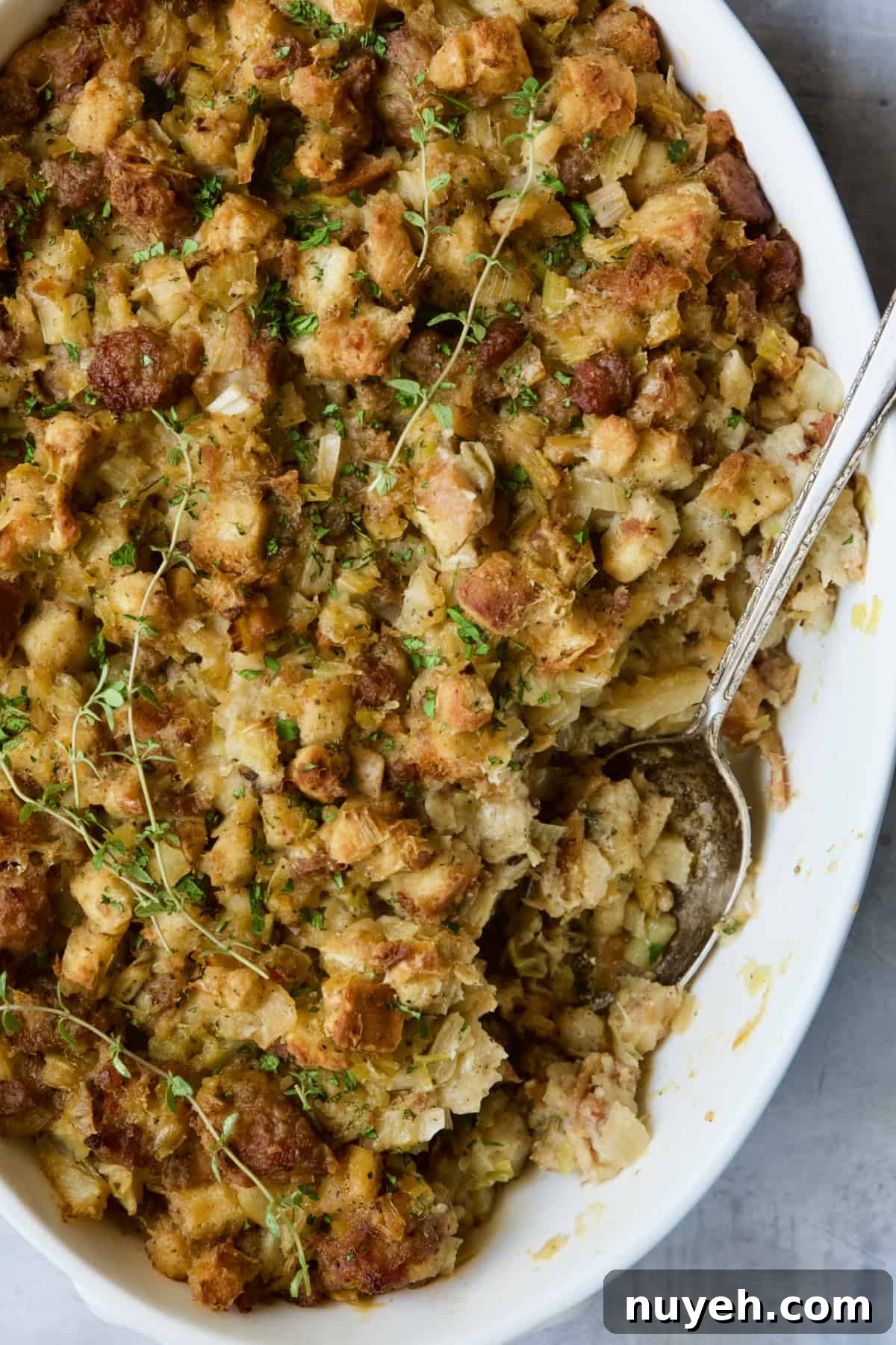 Sausage, Fennel and Leek Stuffing Recipe 2 Sausage Stuffing with Fennel and Leeks in white oval gratin dish with serving spoon.
