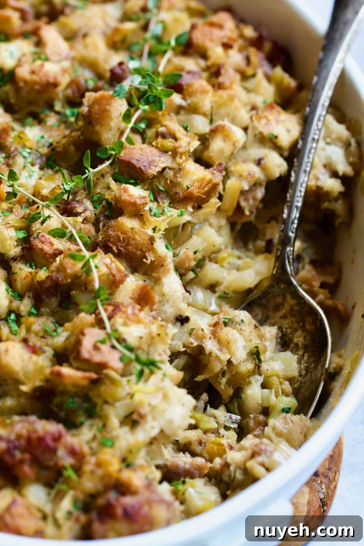 Sausage, Fennel and Leek Stuffing Recipe 7 Sausage Stuffing with Fennel and Leeks in white oval gratin dish with serving spoon.