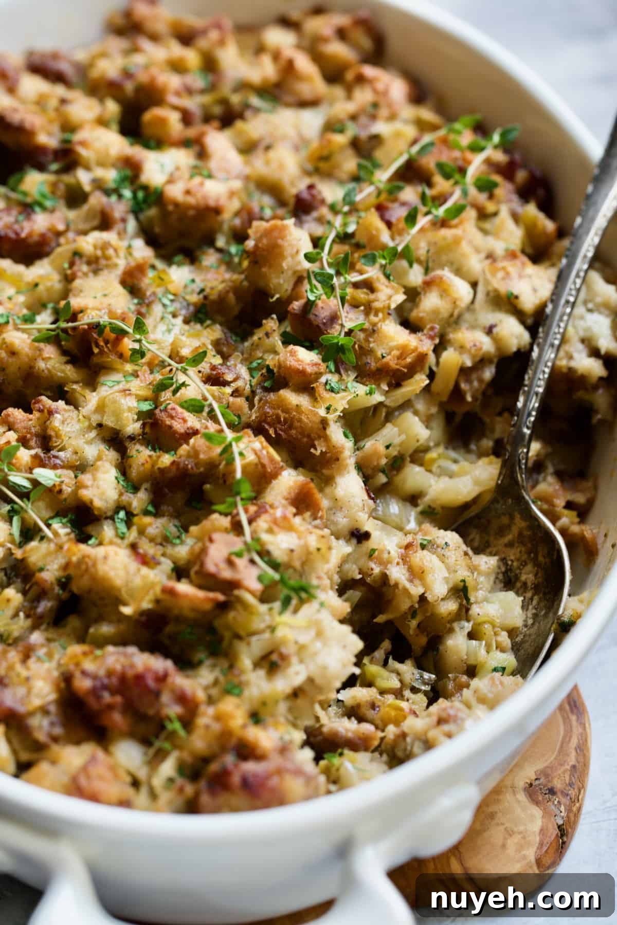 Sausage, Fennel and Leek Stuffing Recipe 3 Sausage Stuffing with Fennel and Leeks in white oval gratin dish with serving spoon.