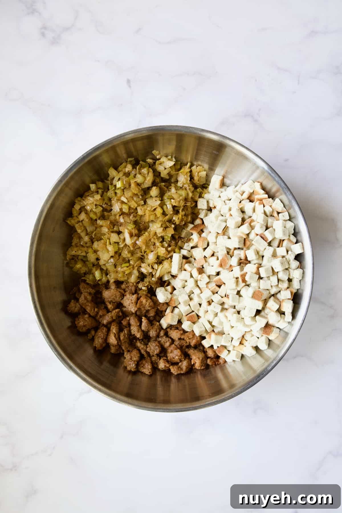 Sausage, Fennel and Leek Stuffing Recipe 6 Cooked ingredients for Sausage Stuffing with Fennel and Leeks in stainless steel bowl before being mixed together.
