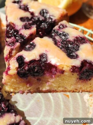 lemon blueberry yogurt cake with glaze sliced on cooling rack