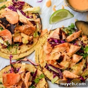 Bang Bang Salmon Tacos on parchment paper with limes on the side.
