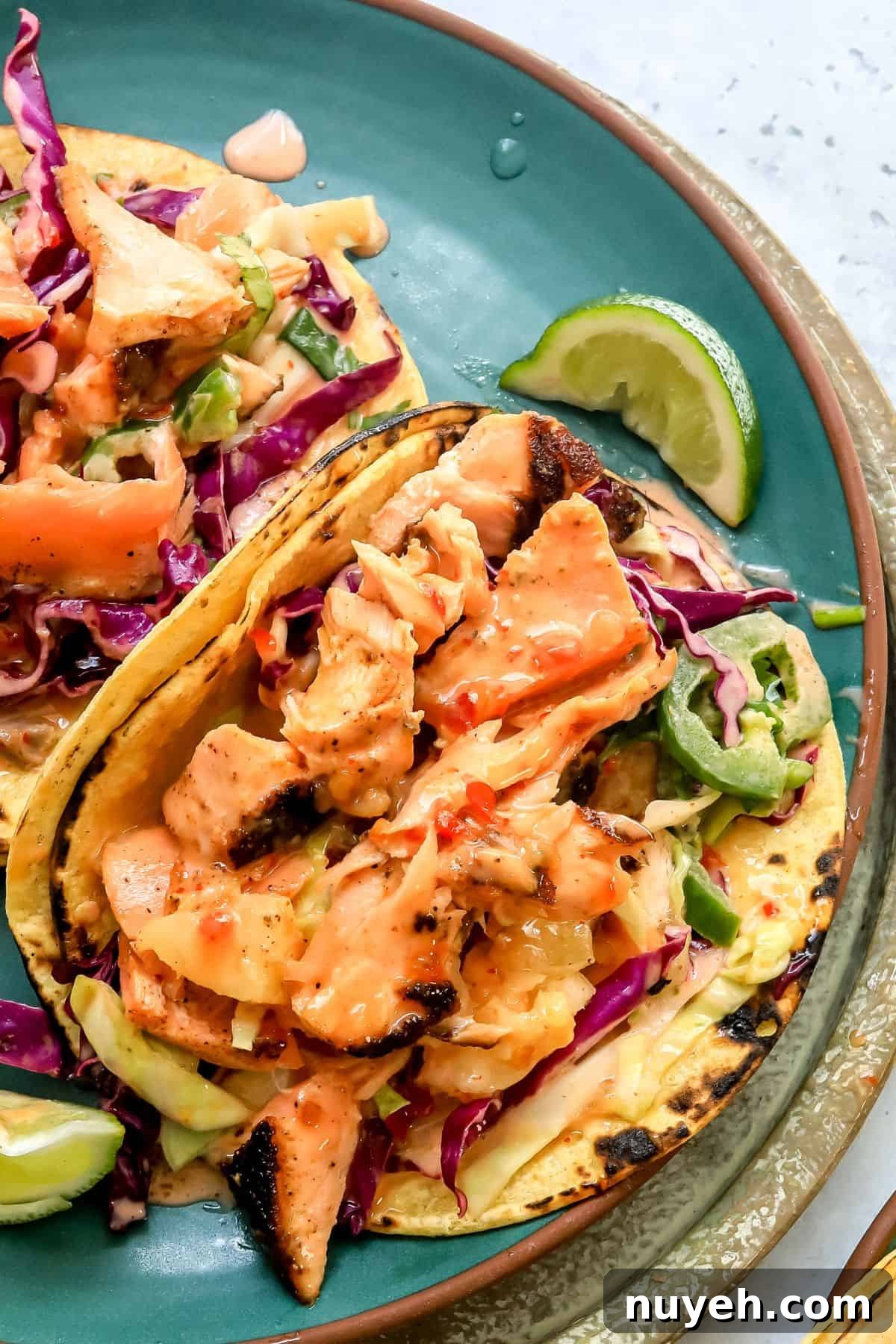 Bang Bang Salmon Tacos on a green plate with sauce and a squeezed lime.