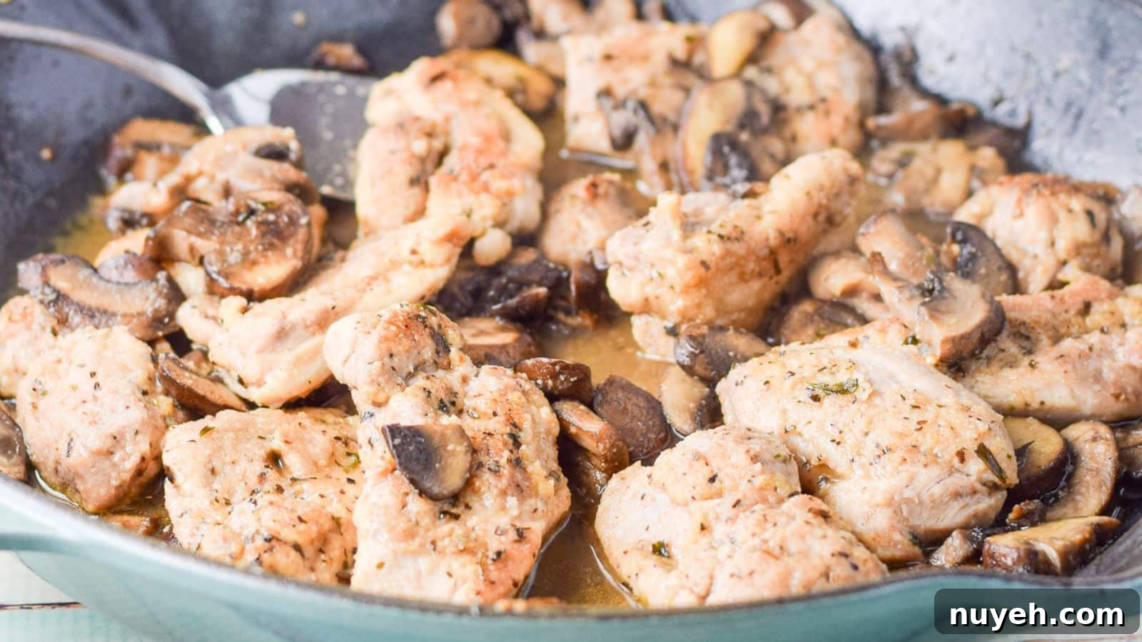 a close up view of chicken pieces in a pan with mushrooms and sauce