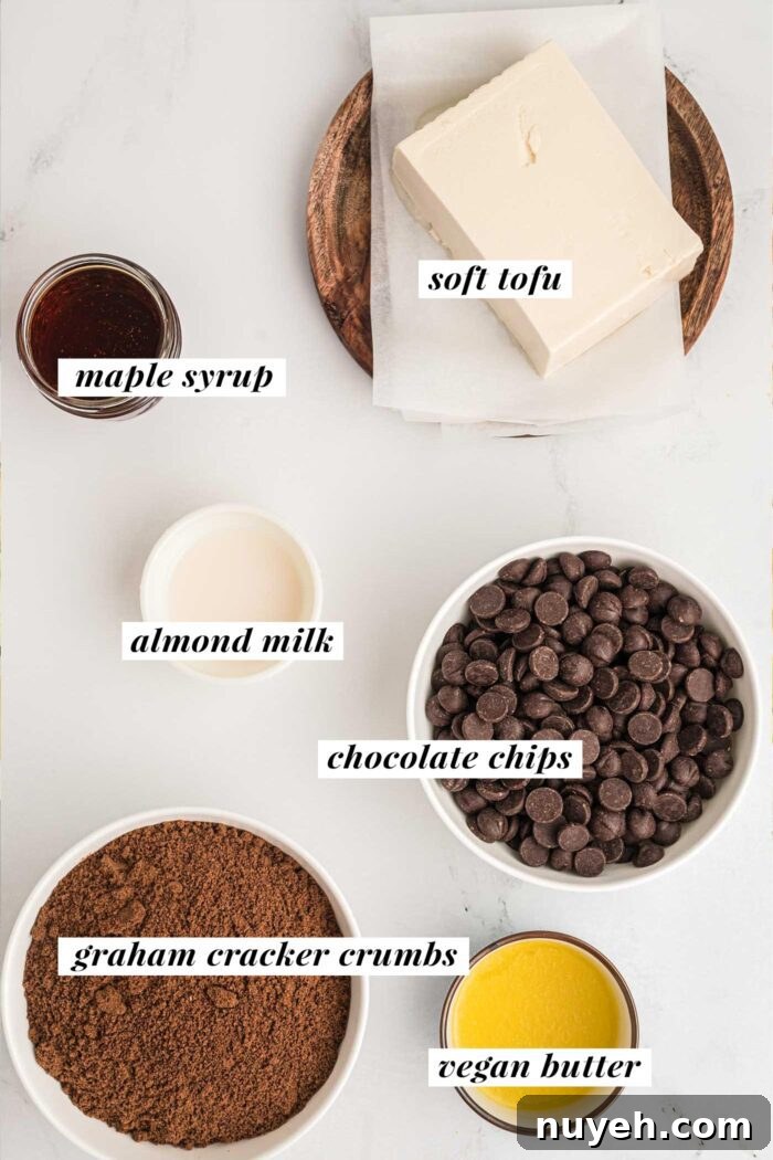 Graham cracker crumbs, melted butter, chocolate chips, almond milk, tofu and maple syrup in small bowls. Each is labelled with text describing the ingredient.