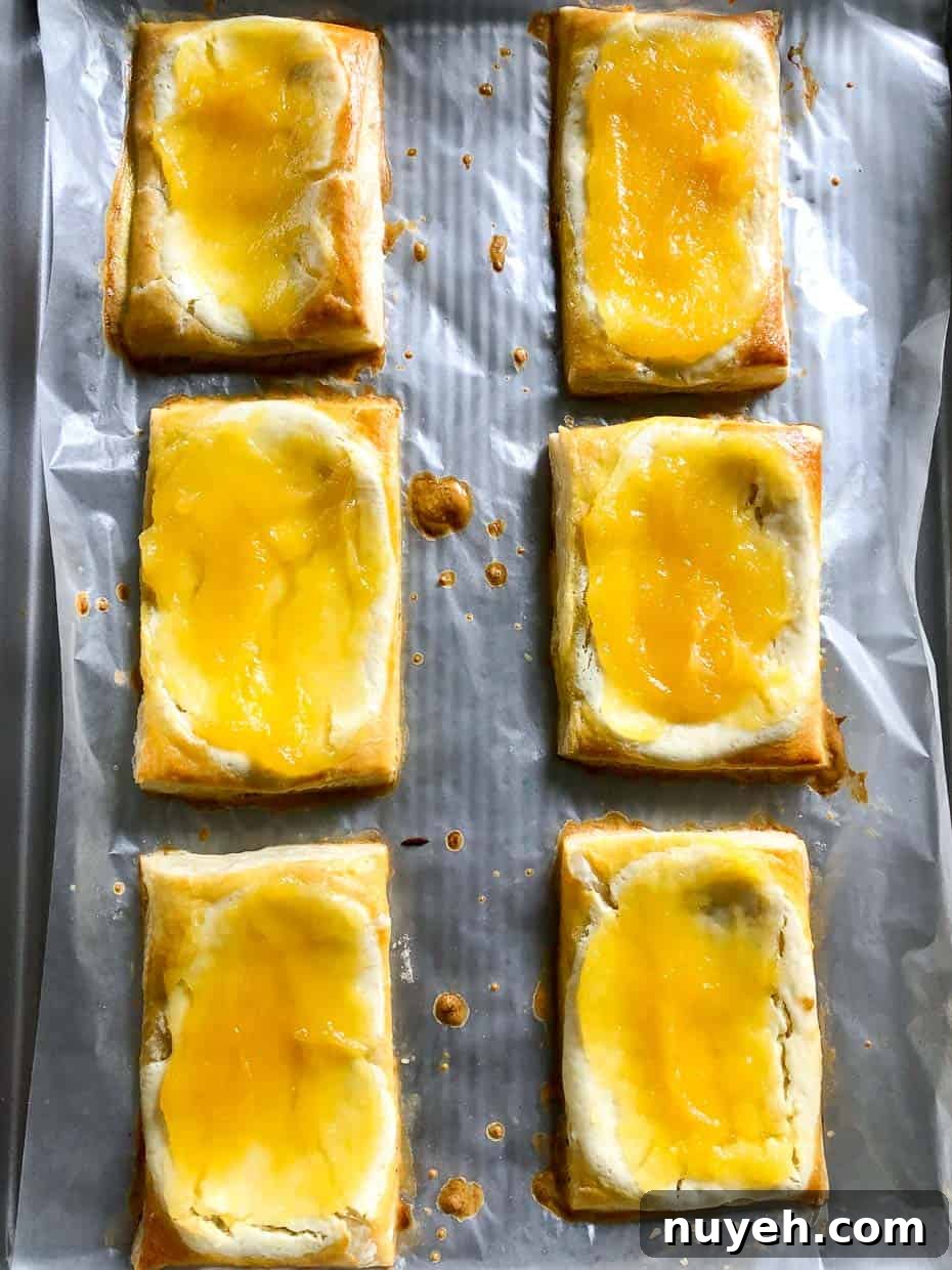Lemon and berry cheesecake puffs on baking sheet with lemon curd 