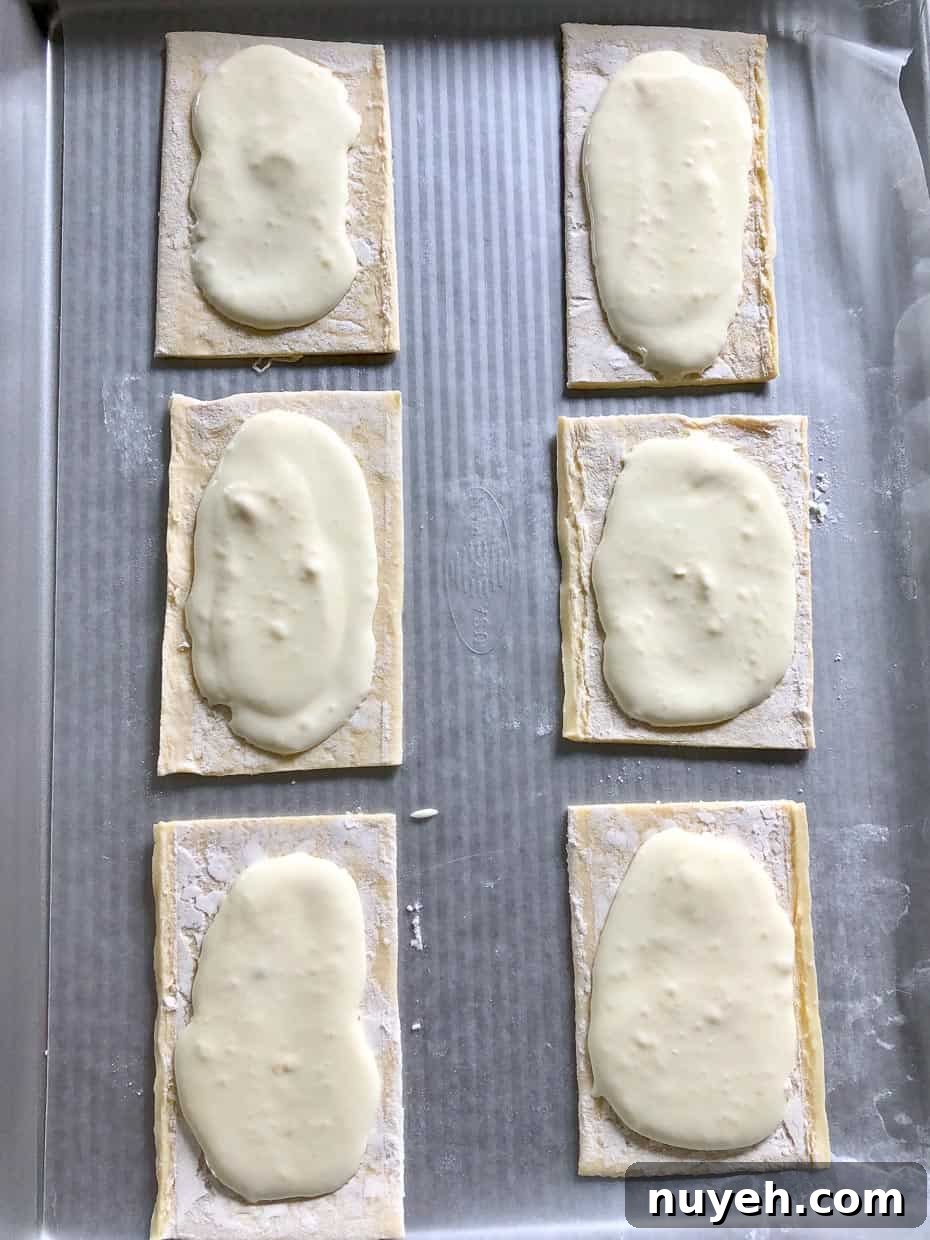 Lemon and berry cheesecake puffs on baking sheet topped with cheesecake mixture