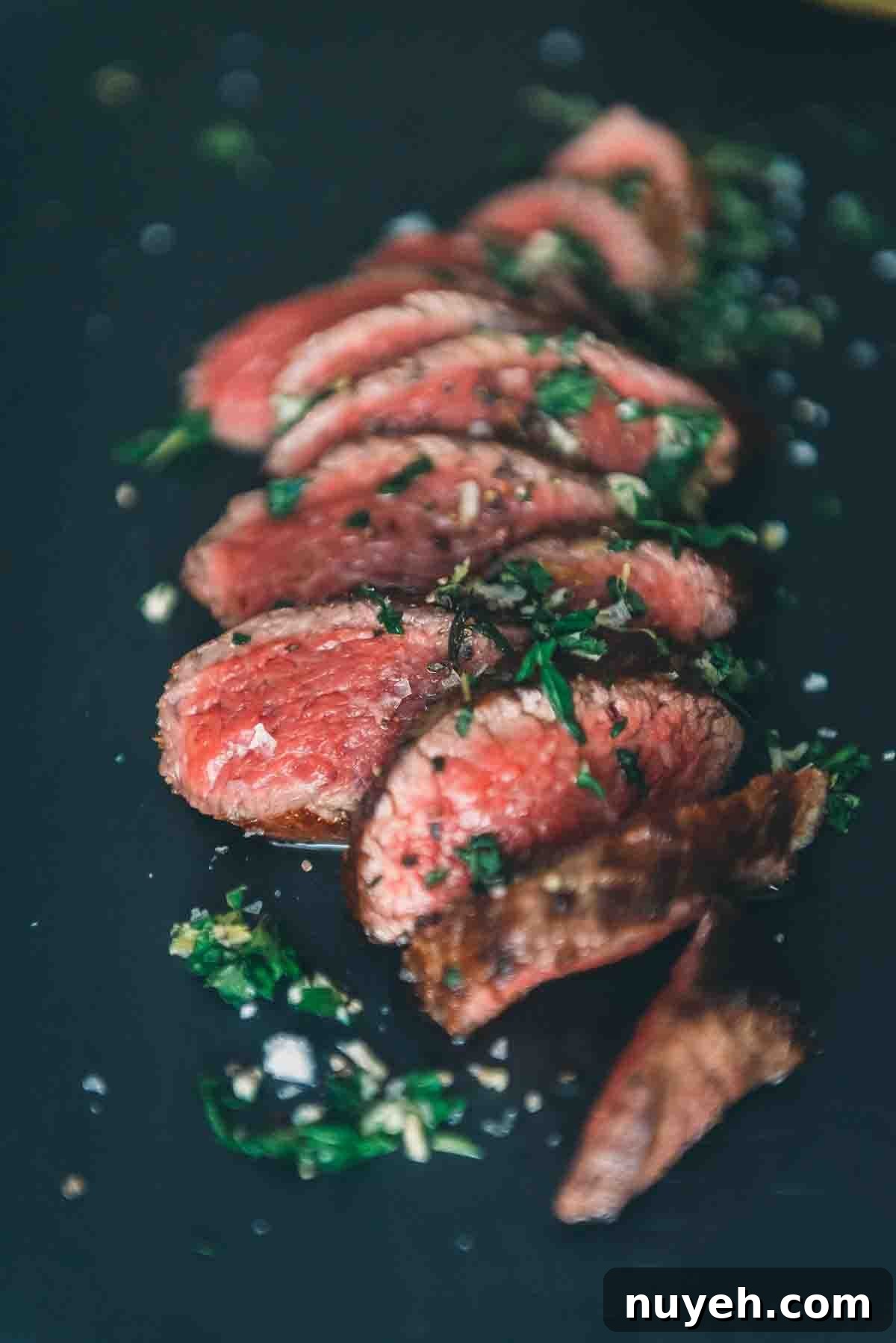 Close up of rare slices of meat with gremolata sprinkled on top. 