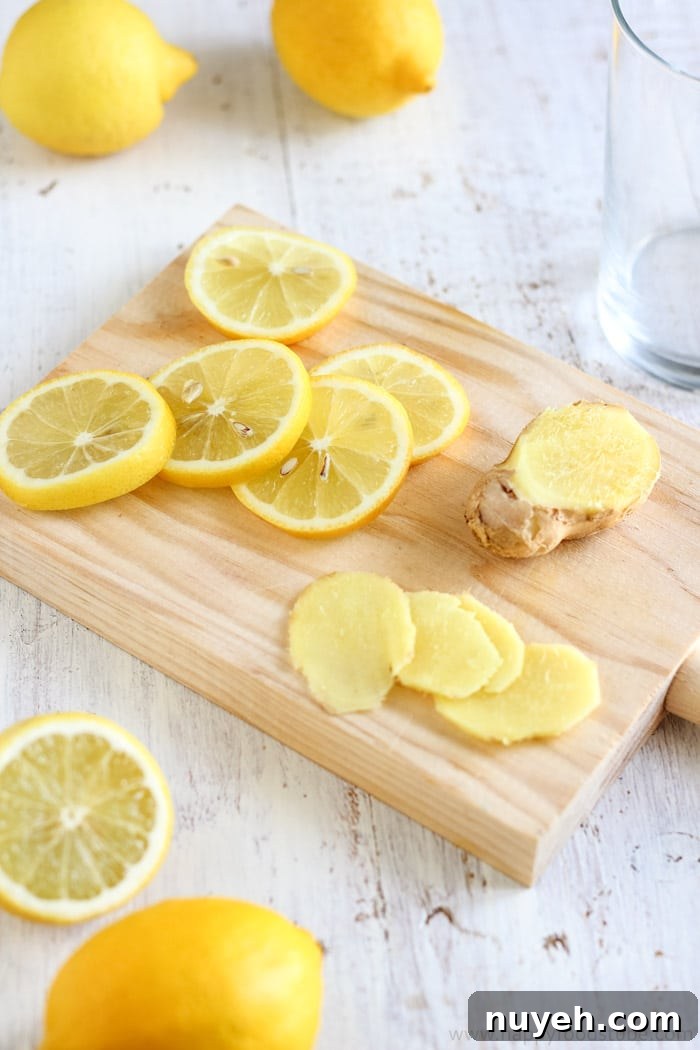 Close-up of fresh lemon rounds and sliced ginger on a wooden cutting board.