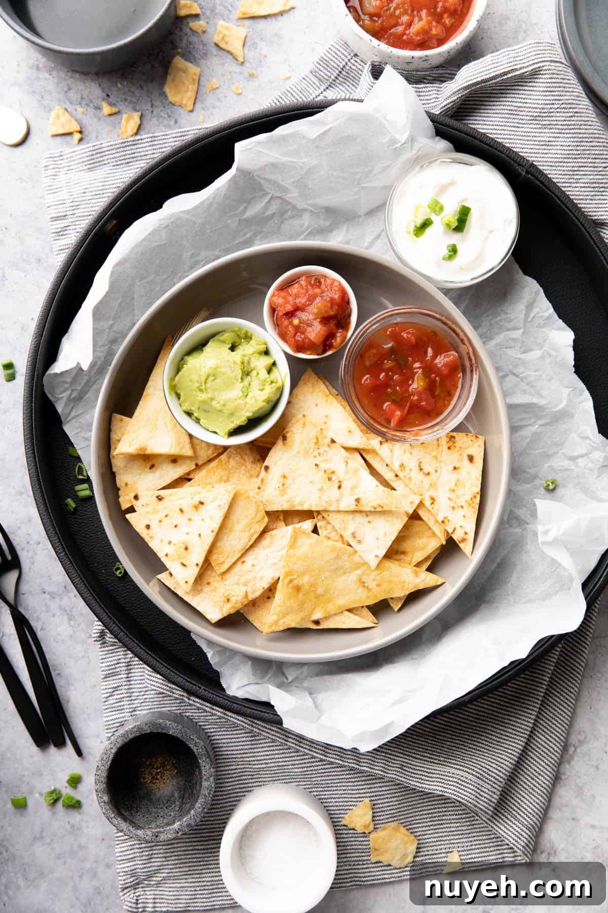 Crispy Homemade Baked Tortilla Chips 9 Mexican-inspired dinner table with guacamole, salsa, sour cream, and utensils