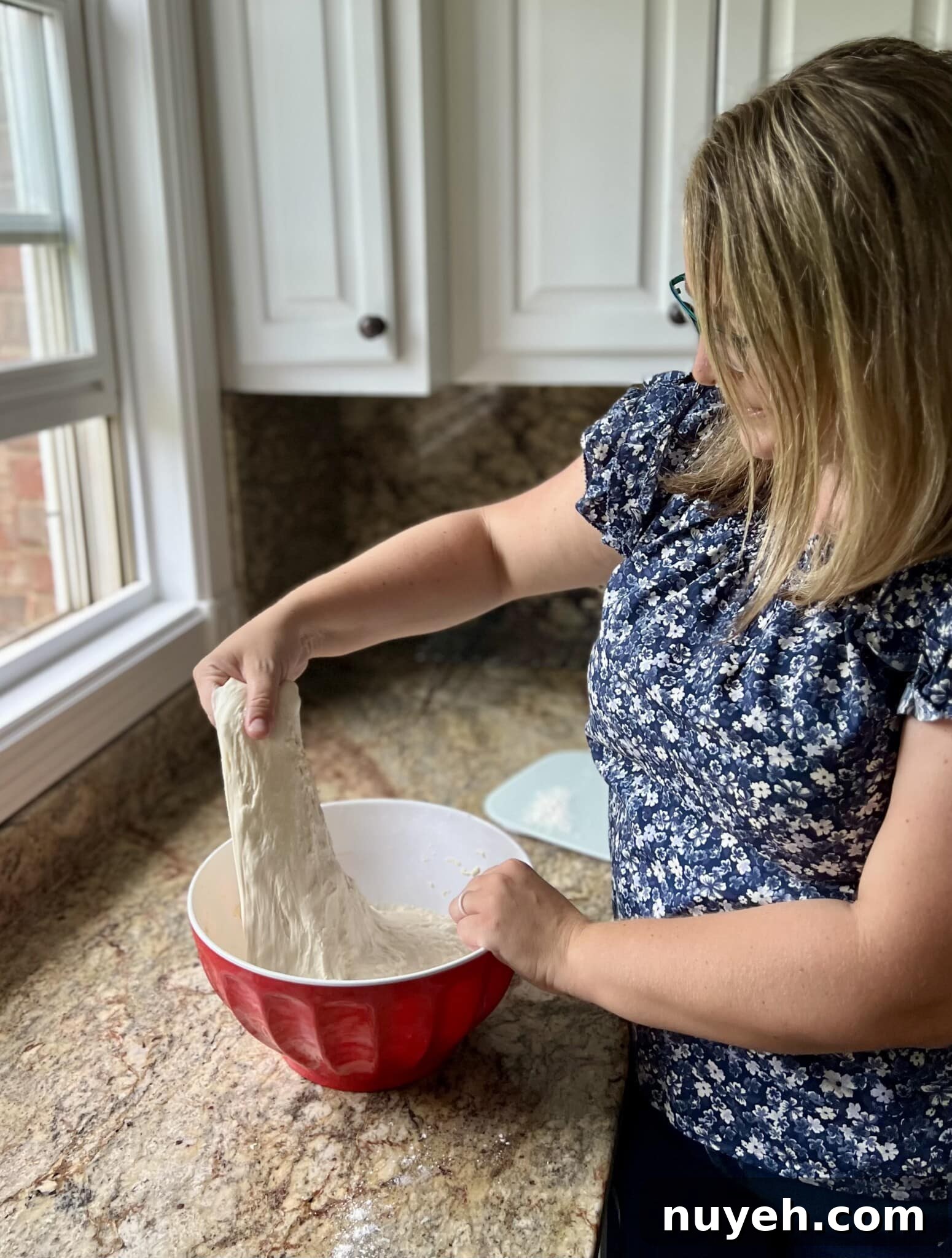 Amy stretch and folding sourdough bread in a bowl on a countertop.