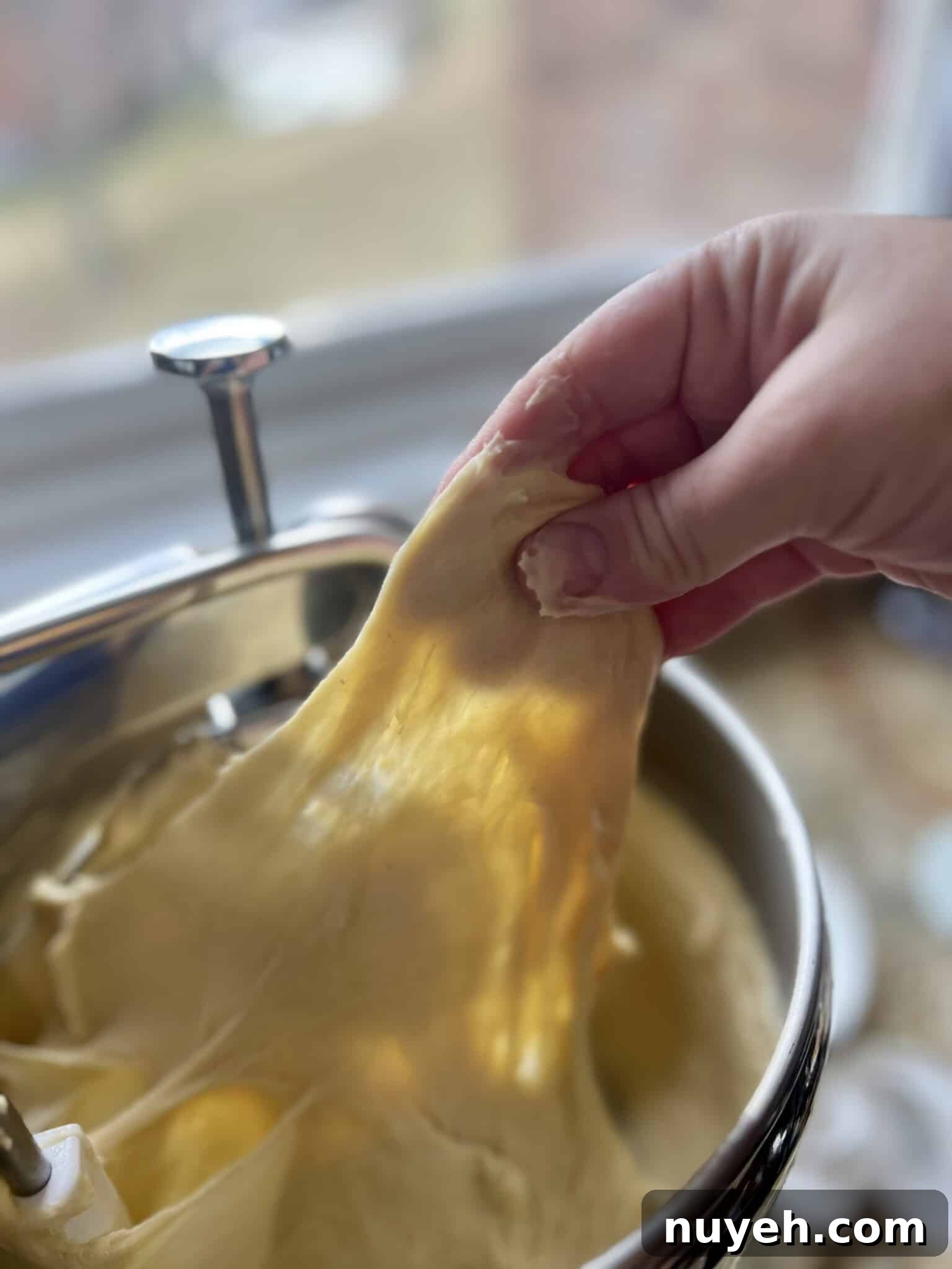 Pulling dough out of a mixer and stretching it thin.