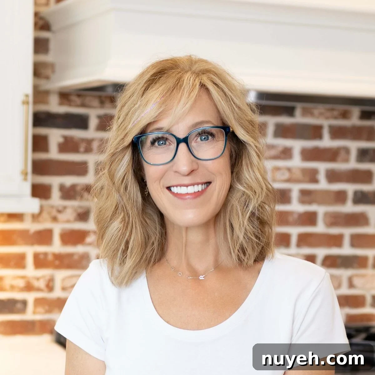 Portrait of the author smiling in front of a brick wall.