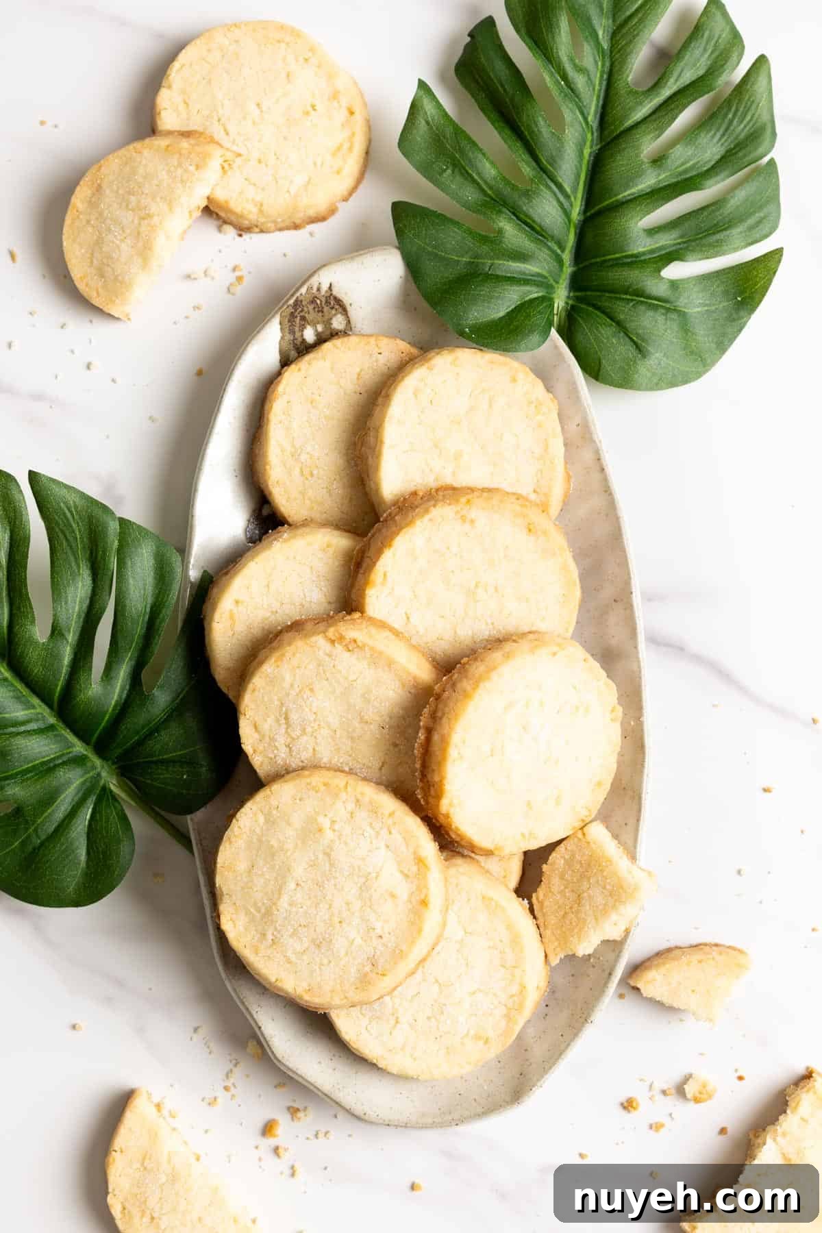 A plate of coconut shortbread cookies on a white marble surface.