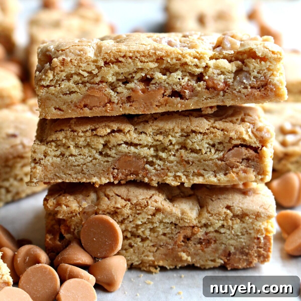 Stack of three butterscotch blondies showing the thick edges and chips inside.