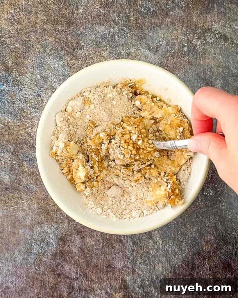A hand mixing the ingredients for the topping in a small bowl with a spoon.