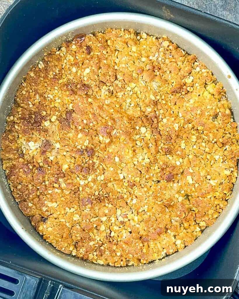 The cooked air fryer rhubarb crisp in the air fryer basket with a golden crust.