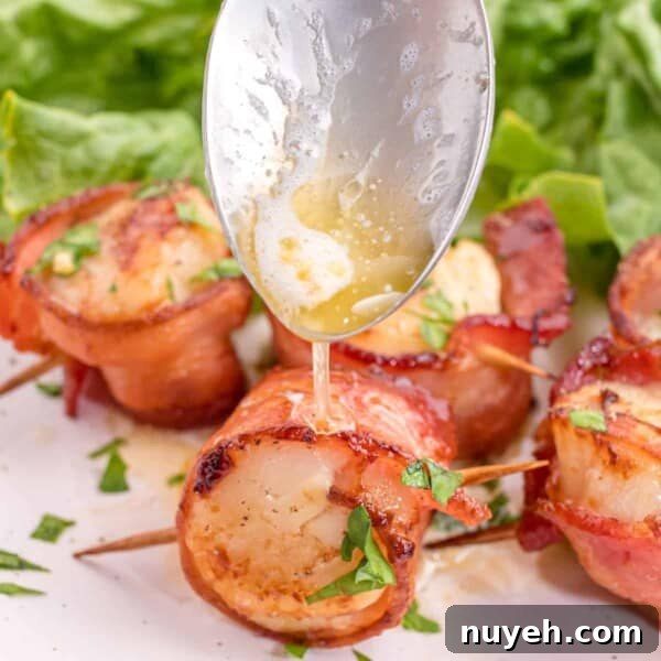 Melted butter being drizzled over air fried bacon wrapped scallps.