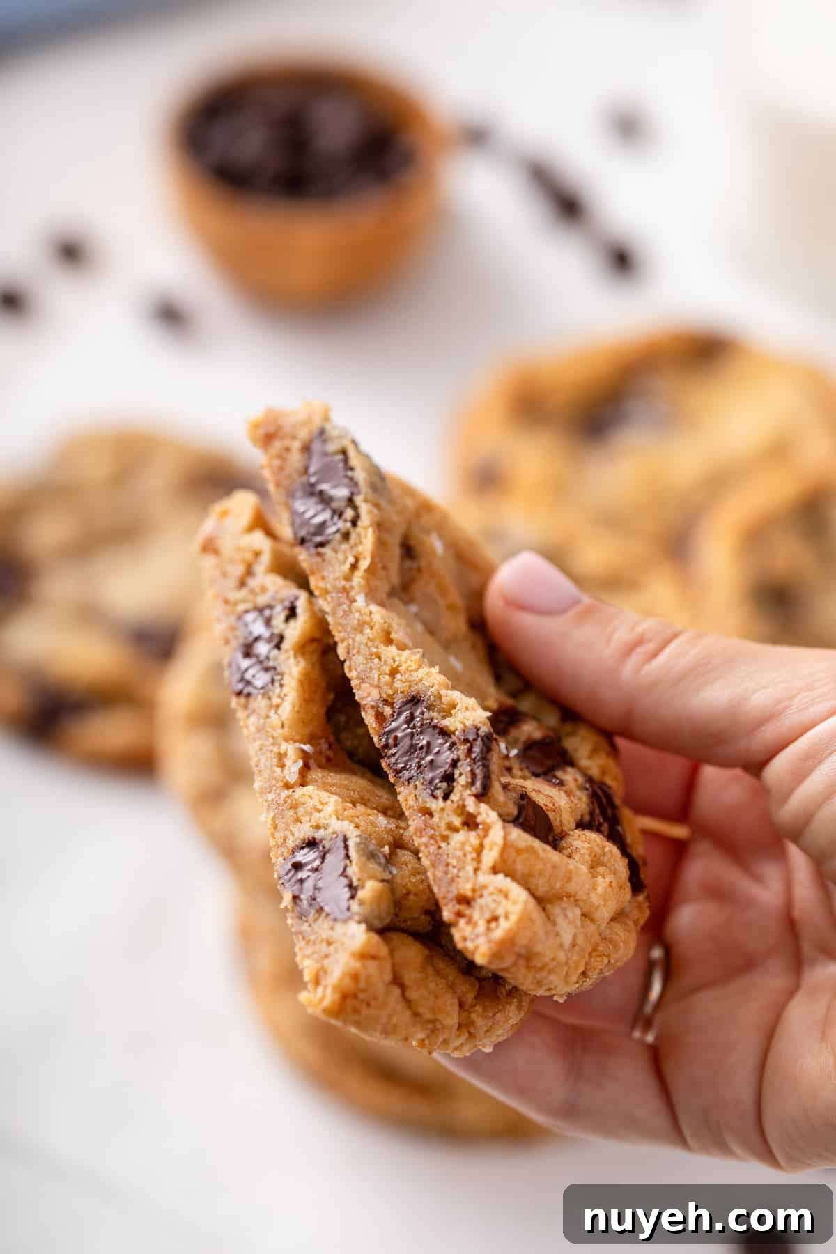 Handing holding up a halved heath bar cookie to show the inside texture.