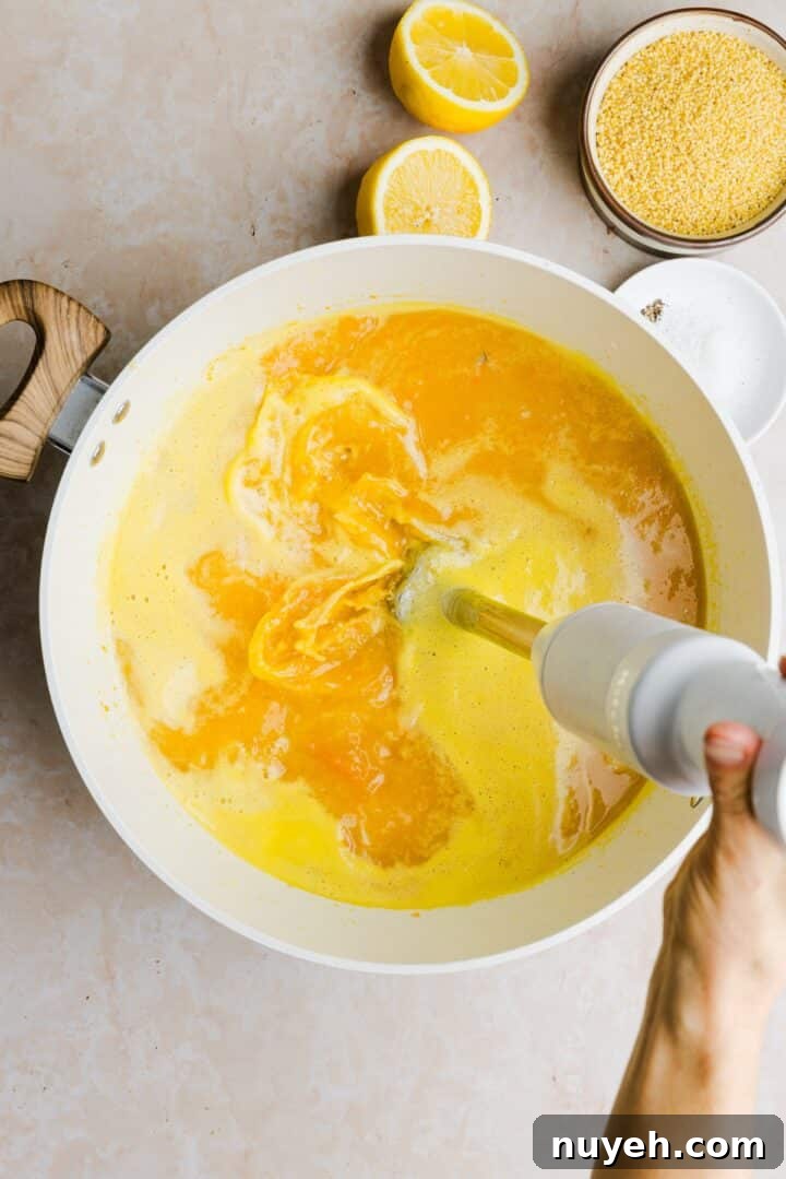 Broth being blended with an immersion blender in a large, white pot
