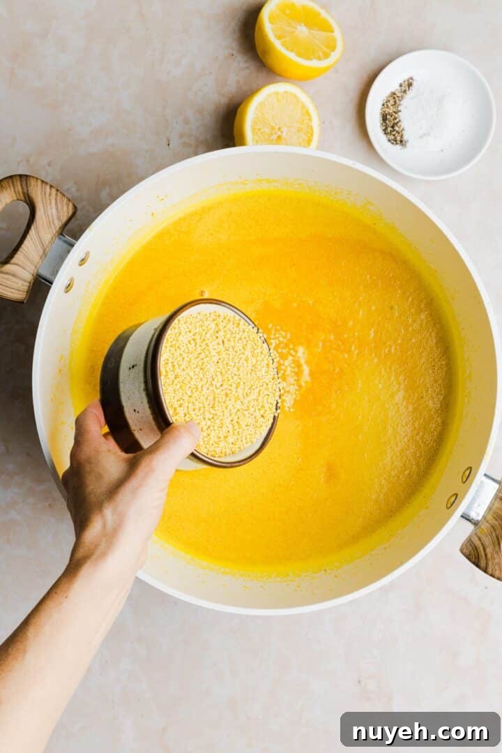 Pastina being poured into a large pot with orange, blended vegetable broth