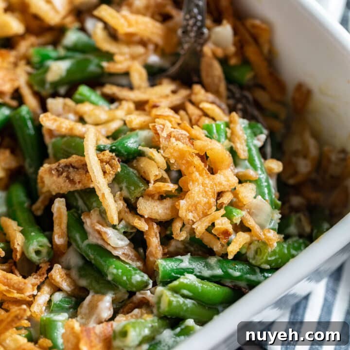 The corner of a pan of green bean casserole with a serving spoon in it.