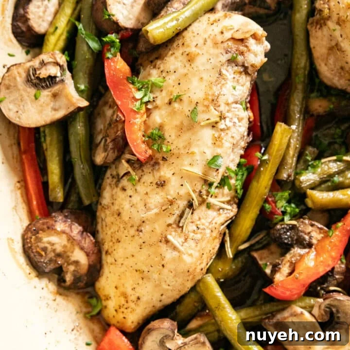 A close up overhead image of the chicken breast nestled in a skillet of green beans, peppers and mushrooms.