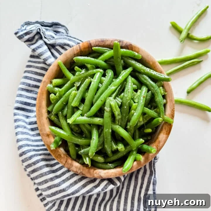 An overhead image of green bean salad in a wooden bowl.